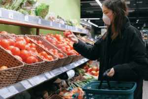 A person in a grocery store shopping for tomatoes