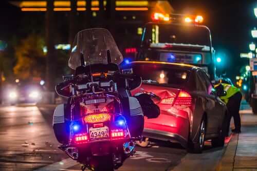 A police motorcycle parked behind a wrecked sedan