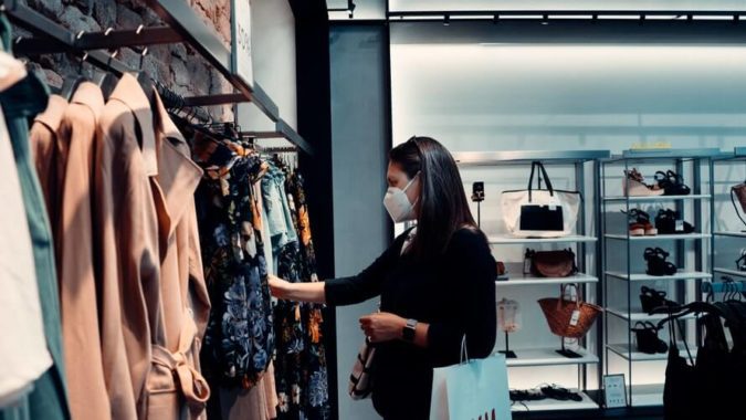 a woman wearing a mask while shopping for clothes
